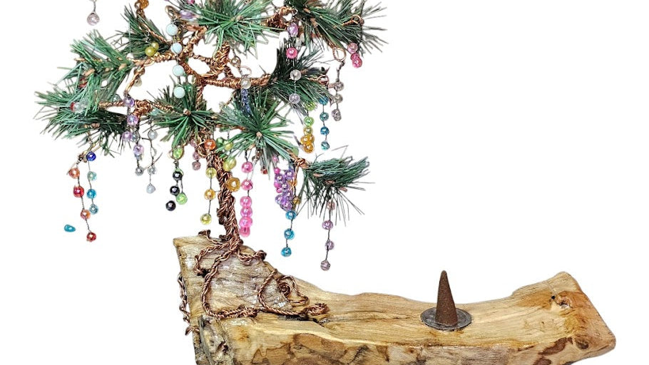 Decorative tree made of greenery and beads on a wooden base with a white background