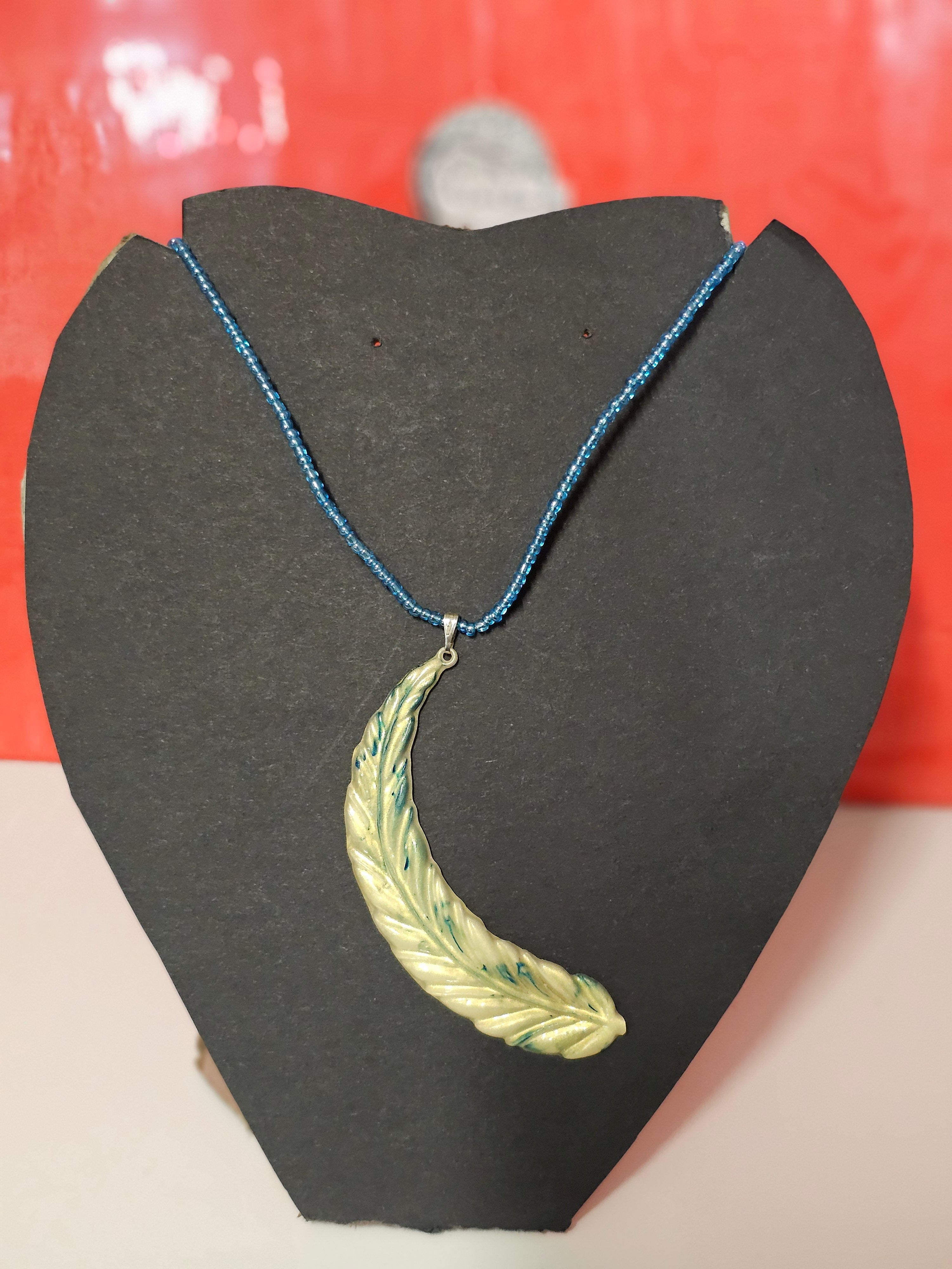 golden feather pendent on blue beaded chain