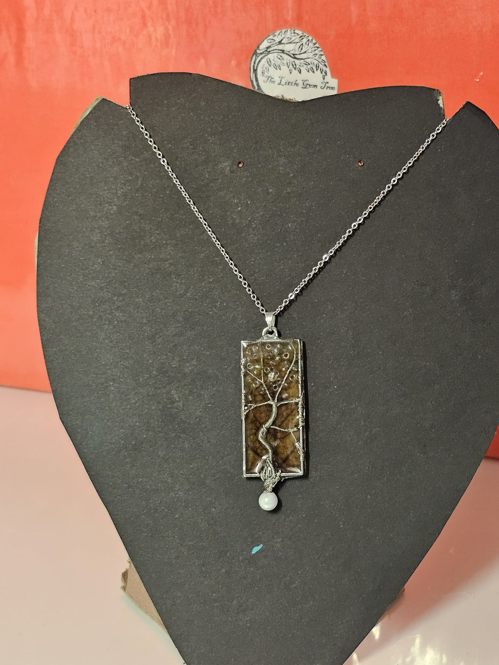 tree of life in a rectangle pendant with an orange leaf background
