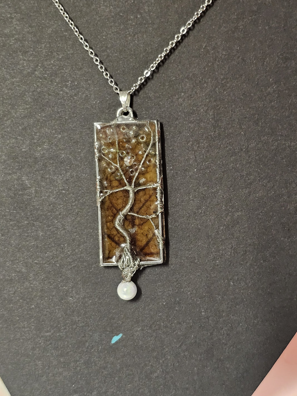 tree of life in a rectangle pendant with an orange leaf background