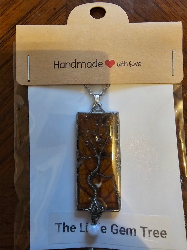 tree of life in a rectangle pendant with an orange leaf background