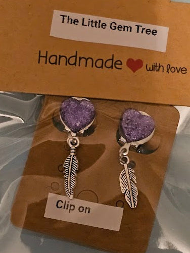 Pair of purple gemstone and silver feather earrings on a 'The Little Gem Tree' branded card.