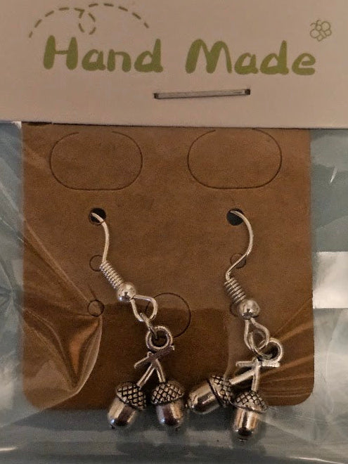 Pair of silver bell-shaped earrings on a 'Hand Made' card against a gray background